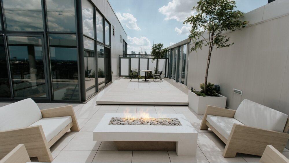 This custom fire pit is surrounded by sofas with white cushions.