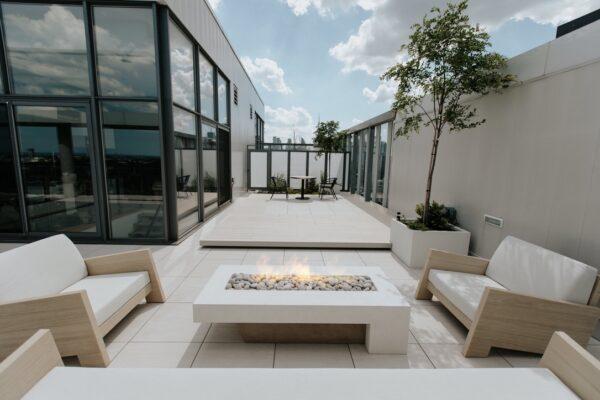 This custom fire pit is surrounded by sofas with white cushions.