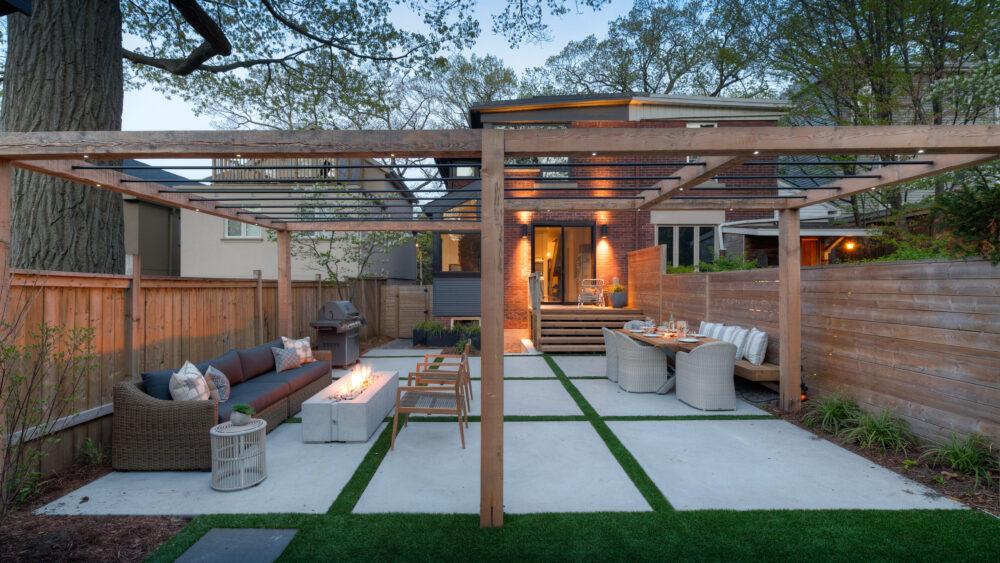 A large backyard with wooden fencing, a wooden covering, sofas and a Dekko fire pit from the Avera range.